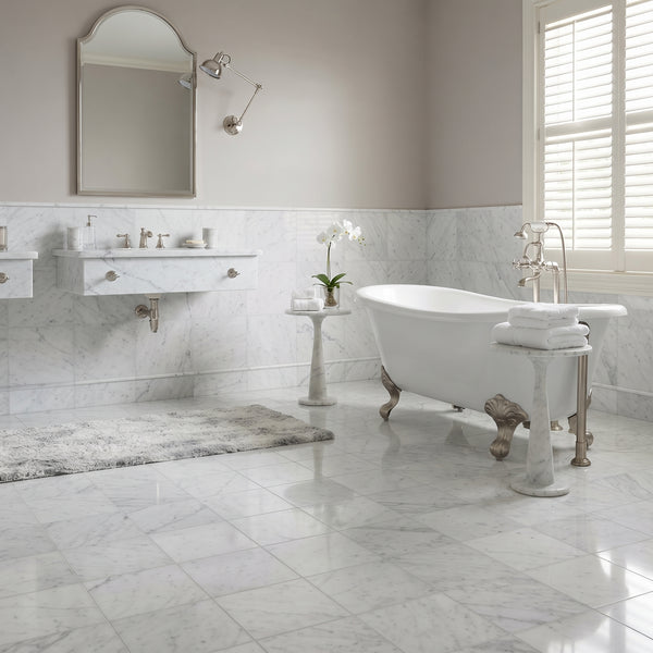 a modern bathroom with a white freestanding bathtub, marble-look tiled walls, a gray marbled bath rug, a white sink vanity with mirror, and a window with white shutters.